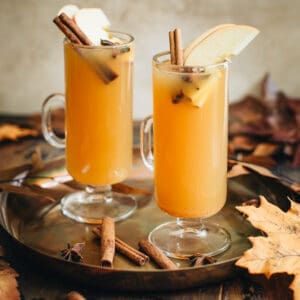 Two Apple Cider Hot Toddy cocktails in tall glass mugs.