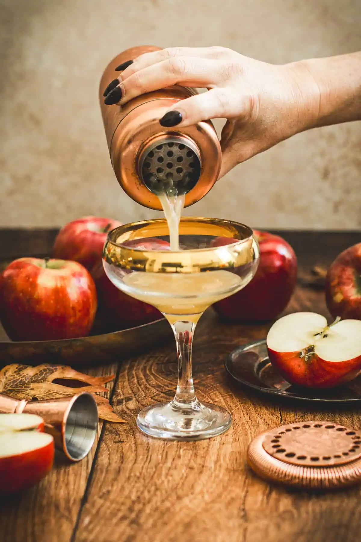Straining an apple cider martini into a cocktail glass.