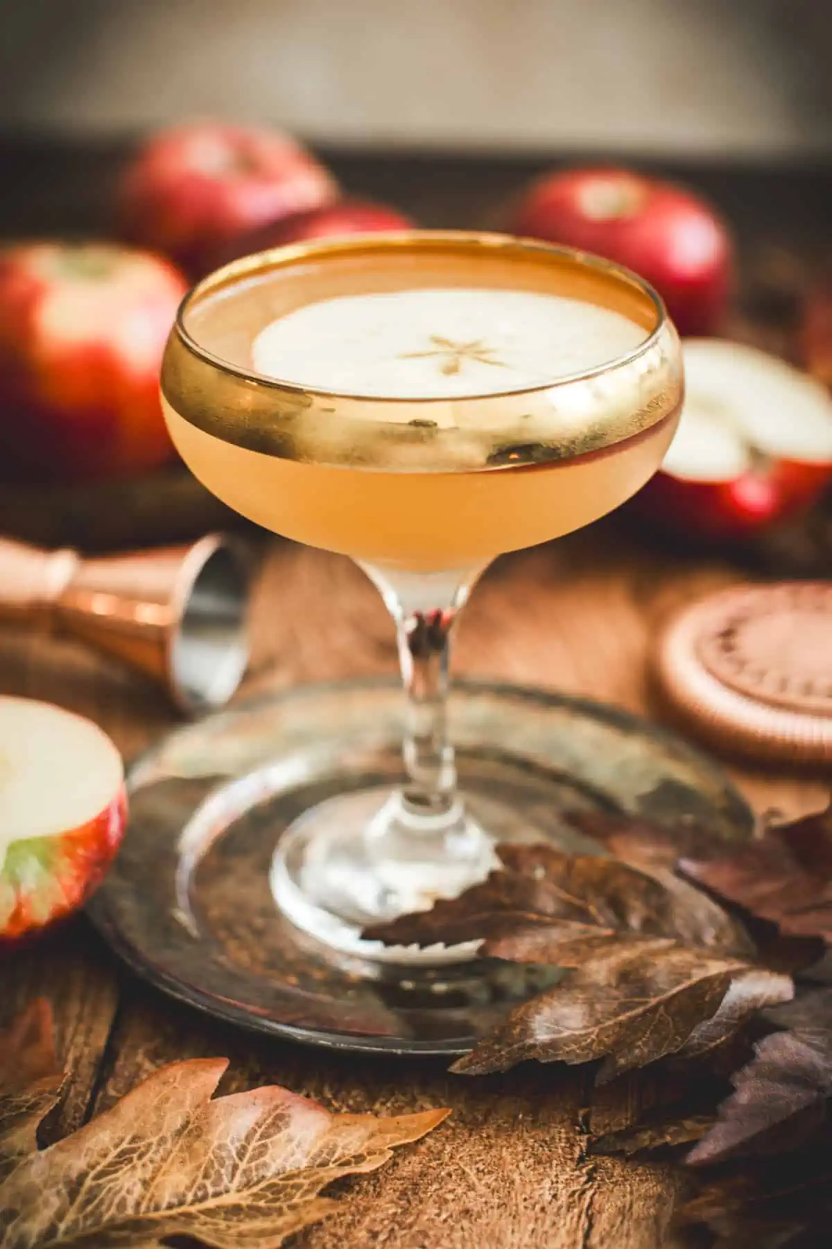 Apple cider martini with an apple slice for garnish in a glass with a gold rim.