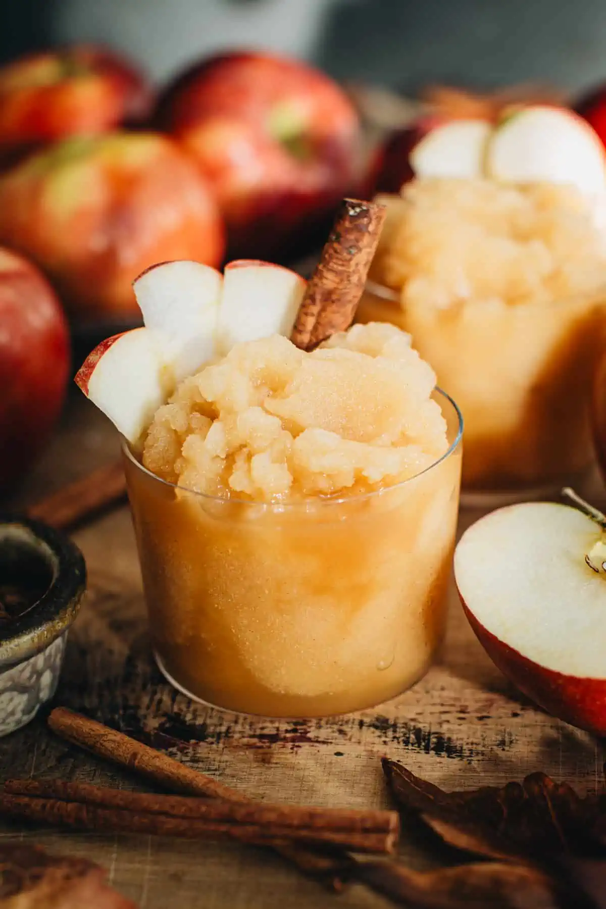 Apple cider slushie with sliced apples and a cinnamon stick.