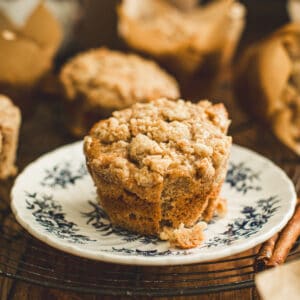 Apple cinnamon muffin with crumble topping on a blue and white plate.