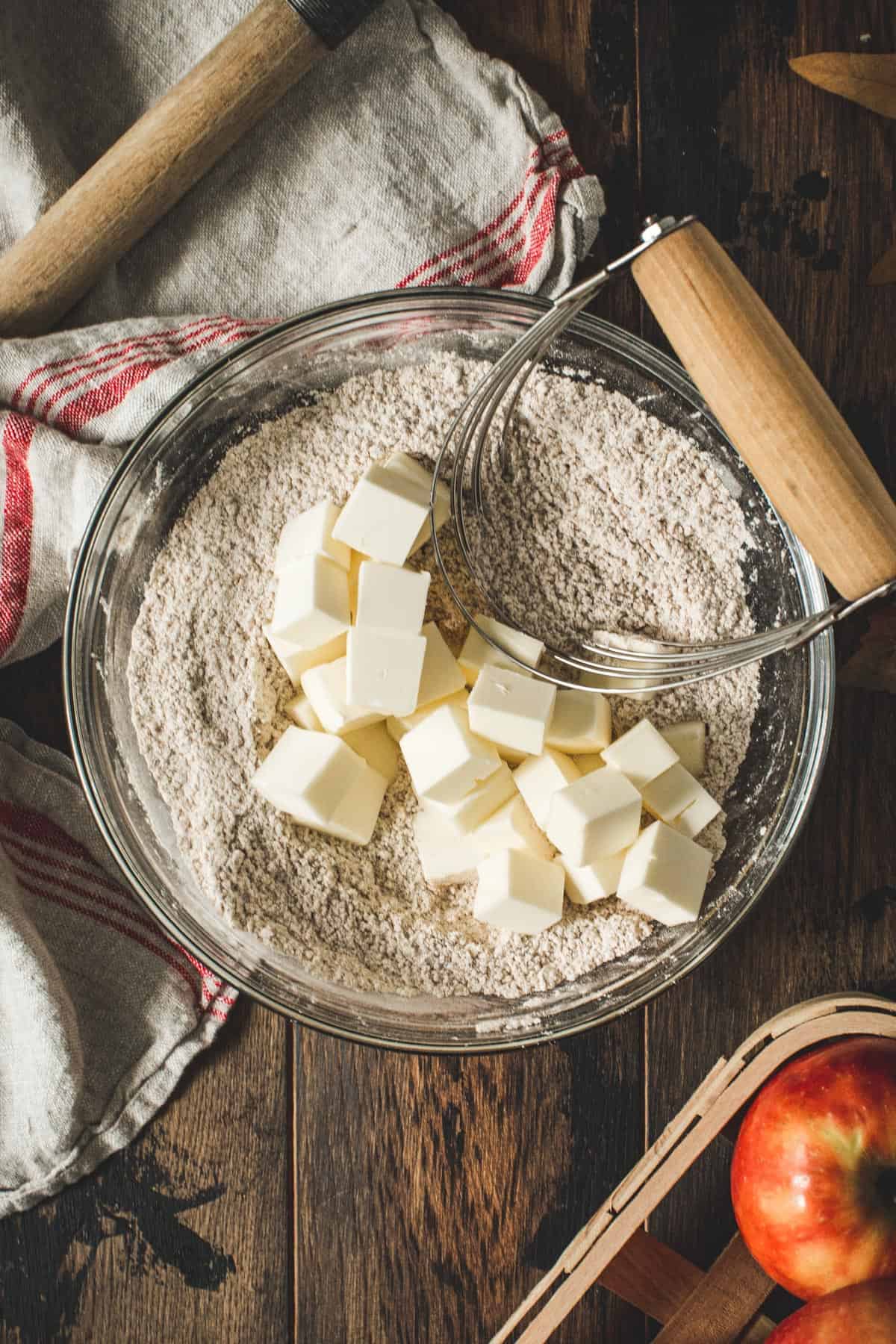 Mixing bowl with the apple crumb cake dry ingredients and butter cubes on top.