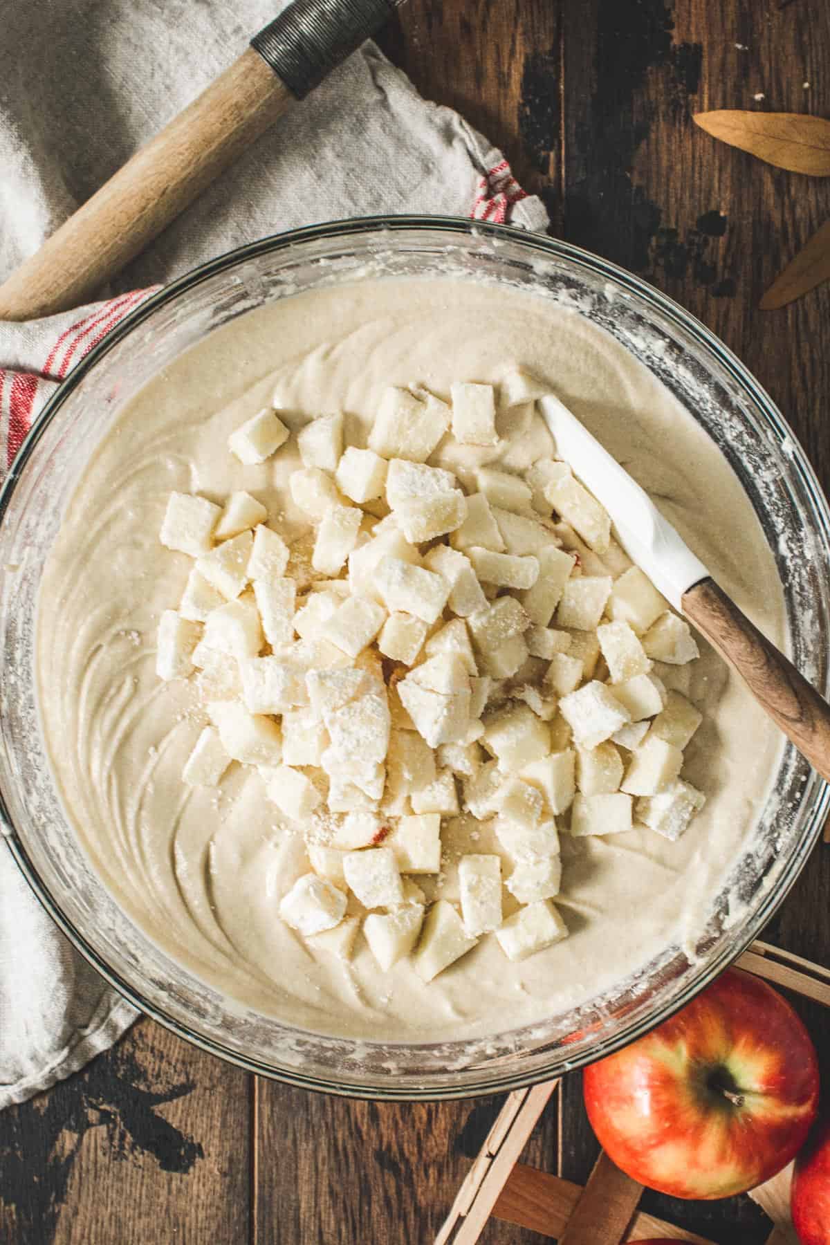 Coated diced apples on top of the apple crumb cake batter.