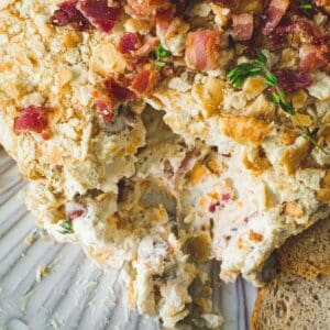 Bacon ranch cheese ball with a scoop taken out on a serving knife.