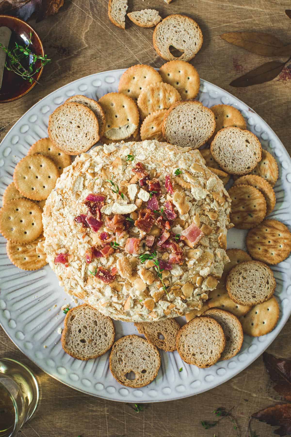 Bacon ranch cheese ball on a plate with crackers around it.