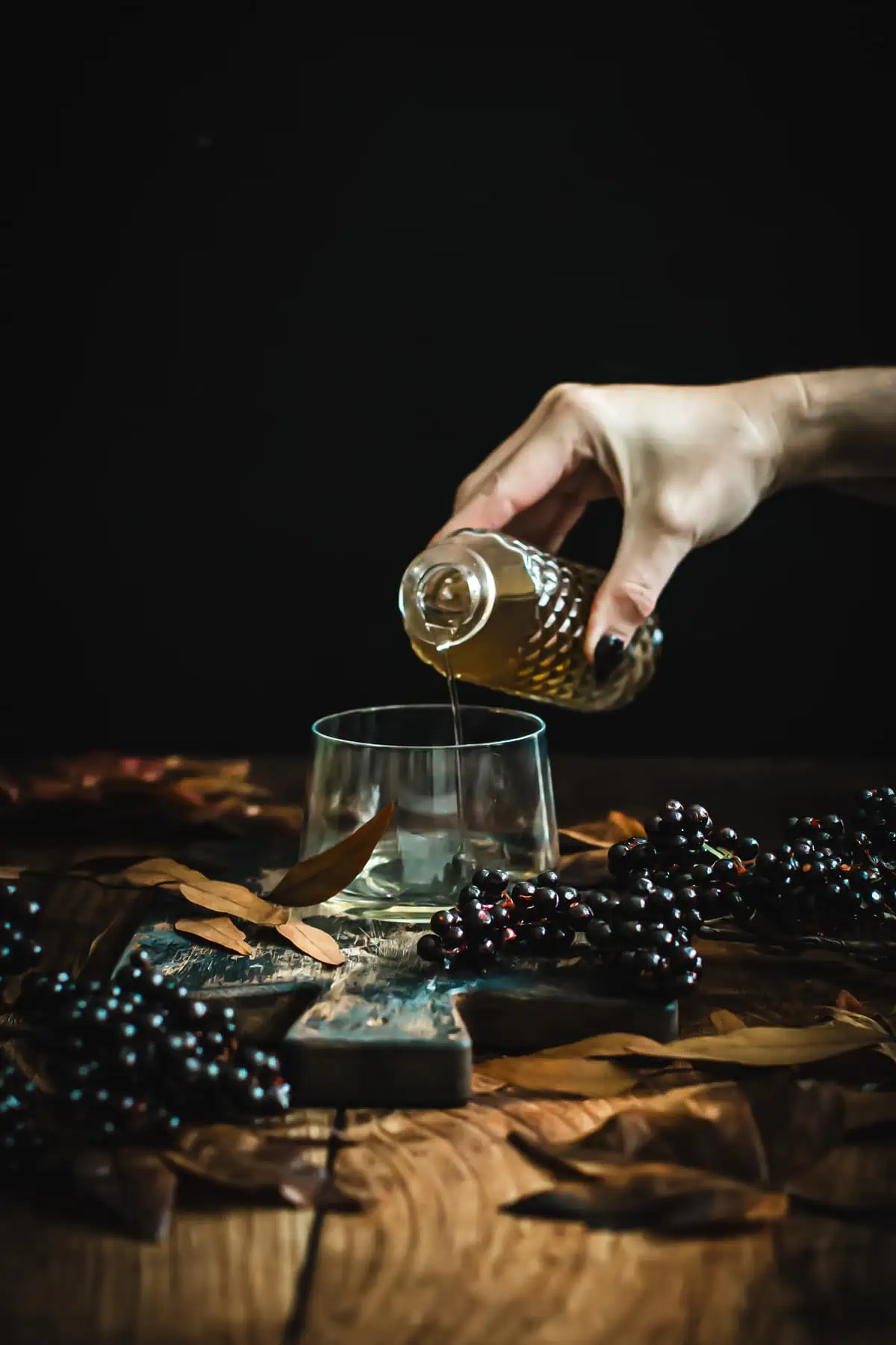 Pouring simple syrup into a glass for black lemonade.