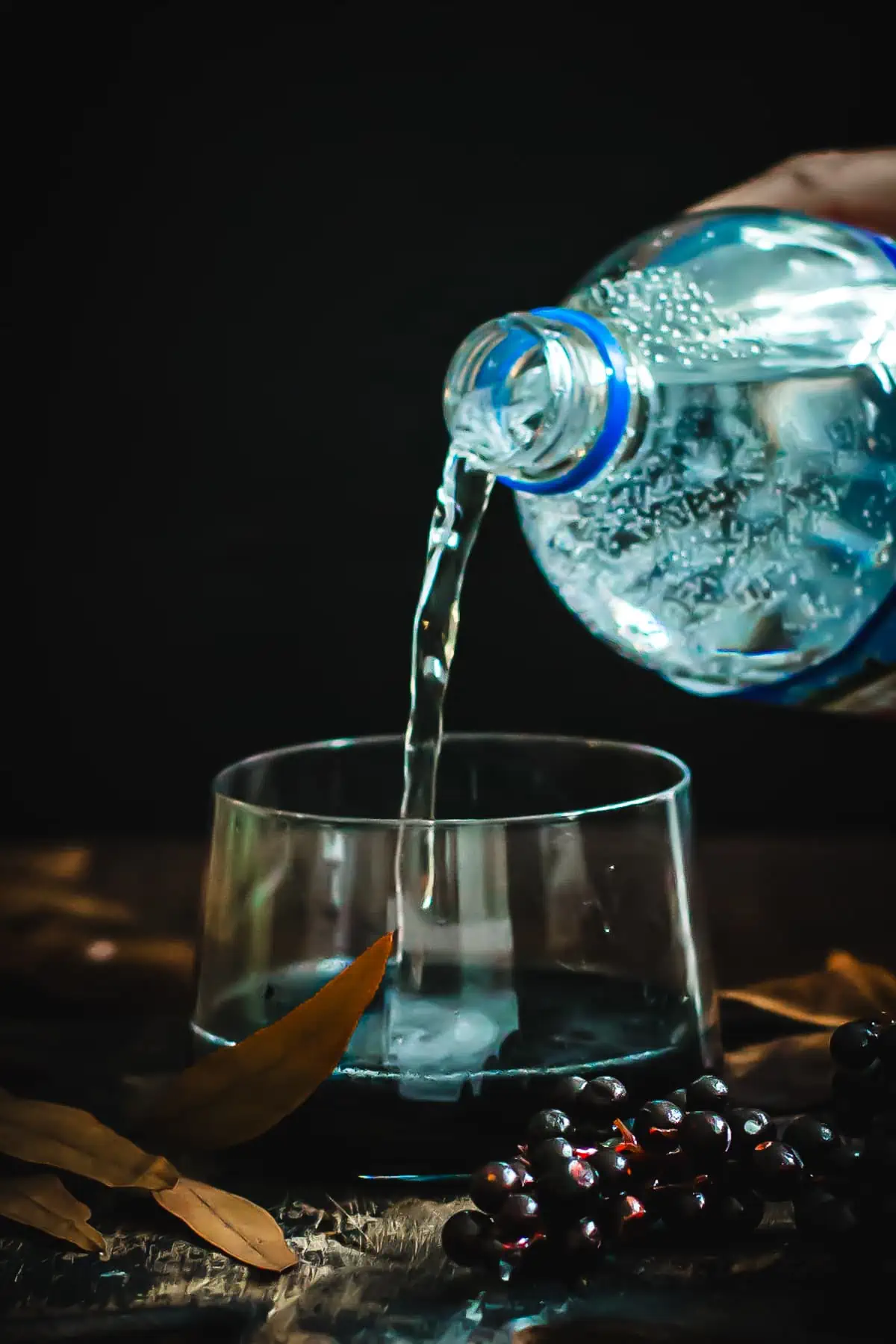 Adding soda water to the glass of black lemonade.