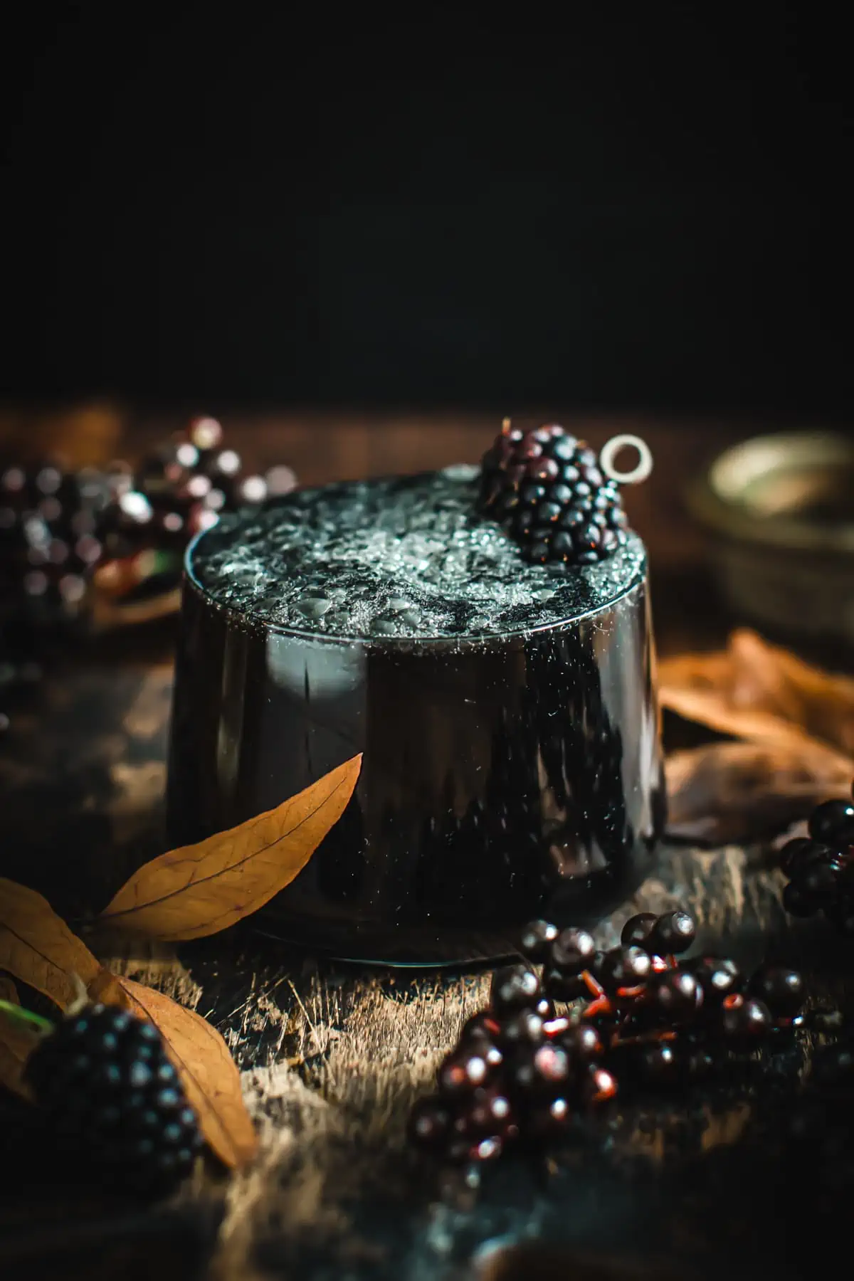 Black lemonade in a glass with a blackberry garnish.