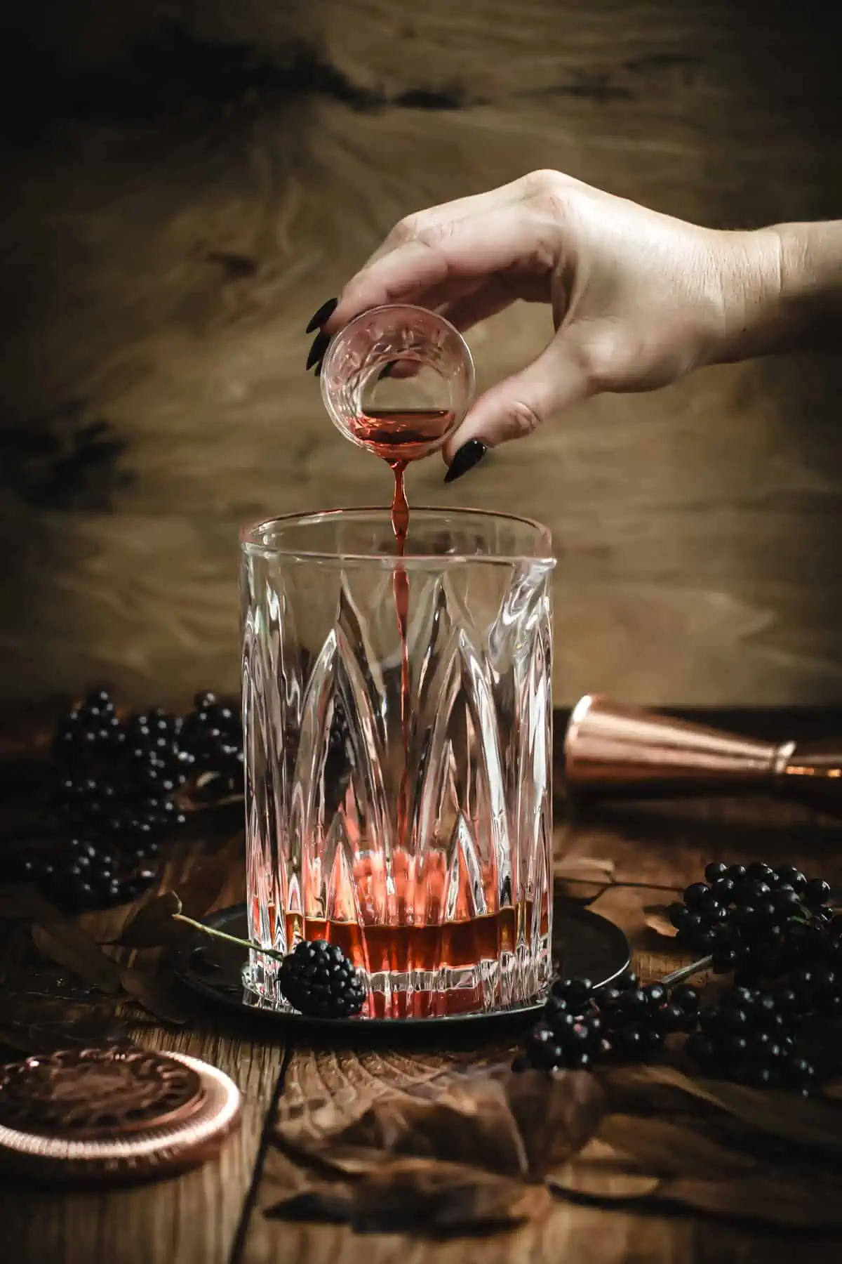 Add the ingredients for a Black Manhattan to a cocktail mixing glass.