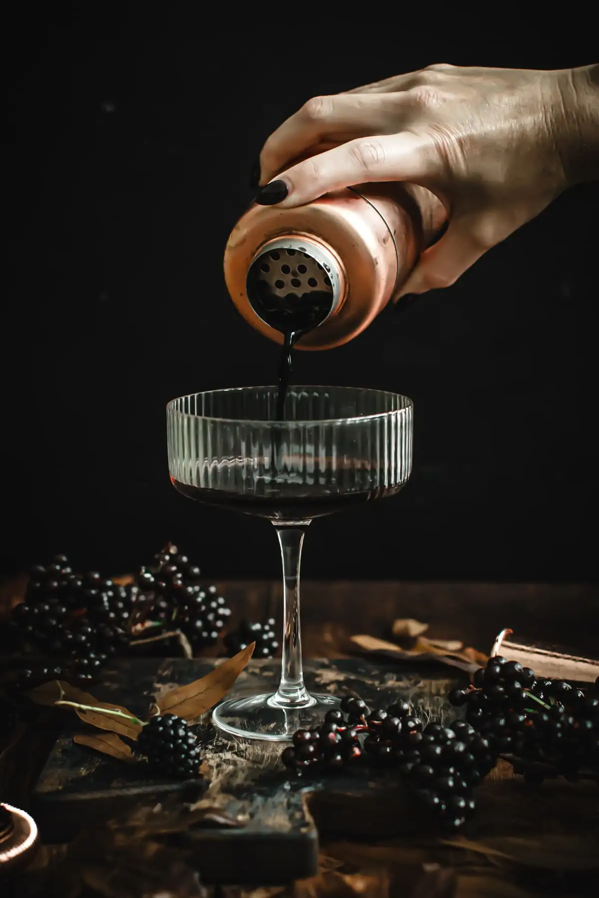 Straining the mixture for a black martini into a martini glass.