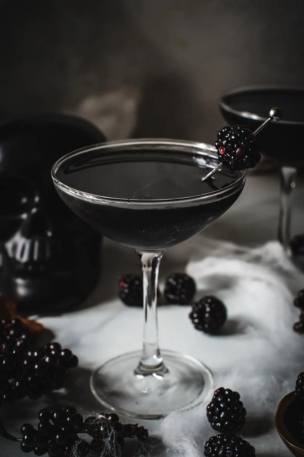 The Black Widow Cocktail in a martini glass with a blackberry for garnish.