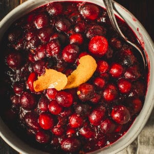 Bourbon cranberry sauce topped with orange peel in a white bowl.