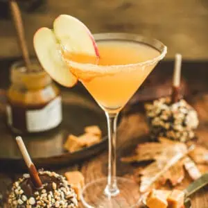 Caramel apple martini in a martini glass with an apple garnish.