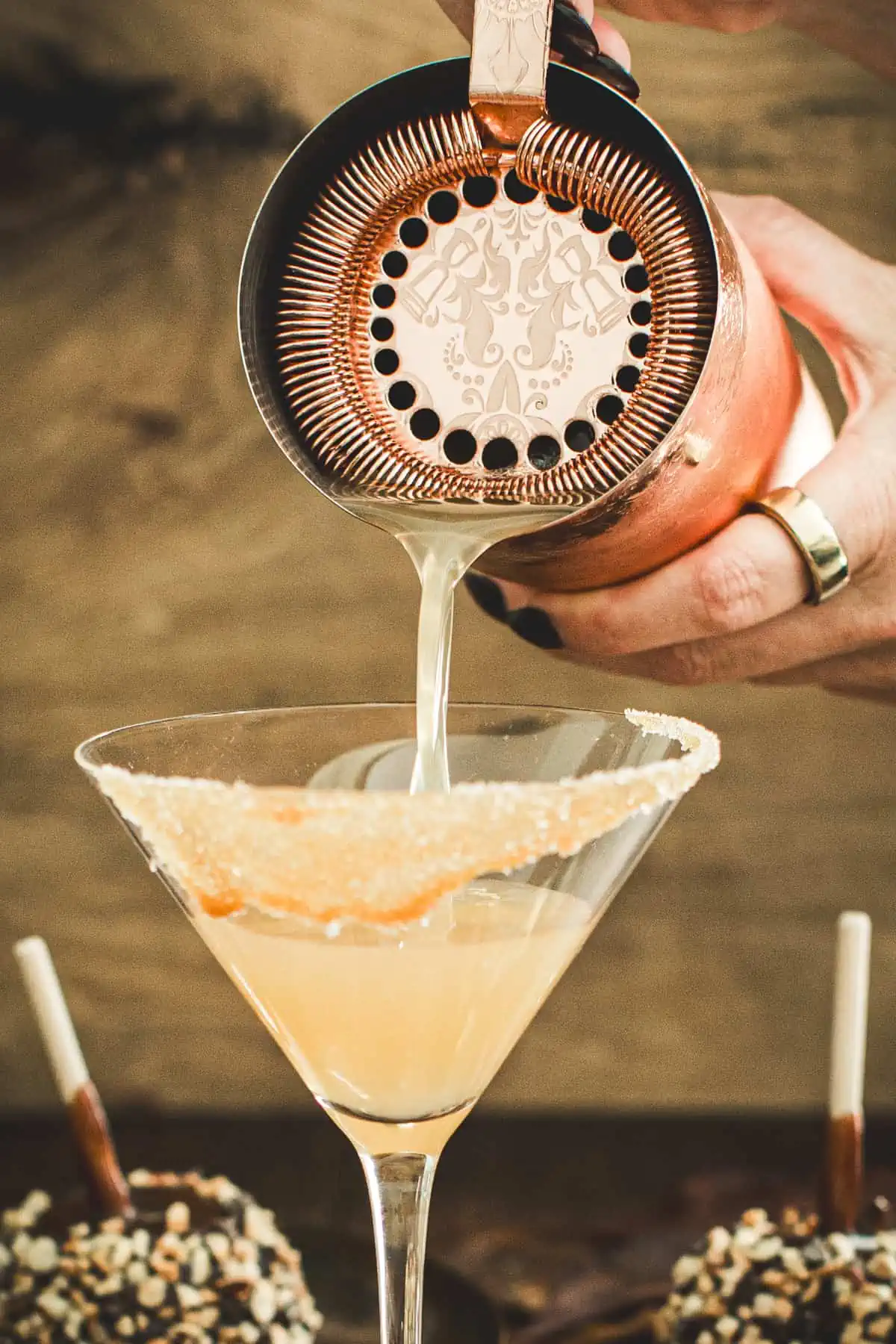 Straining caramel apple martini into a martini glass.