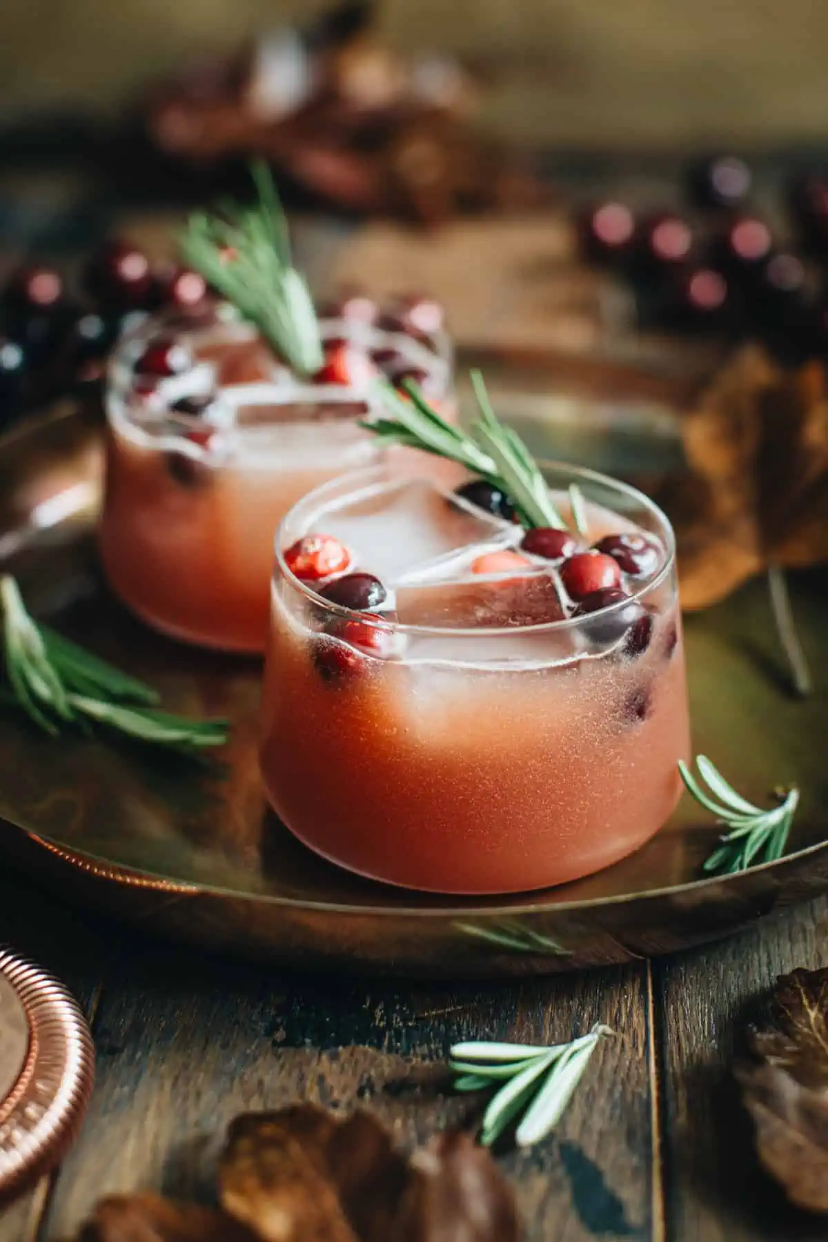 Cranberry bourbon cocktails with fresh cranberries and rosemary sprigs for garnish.