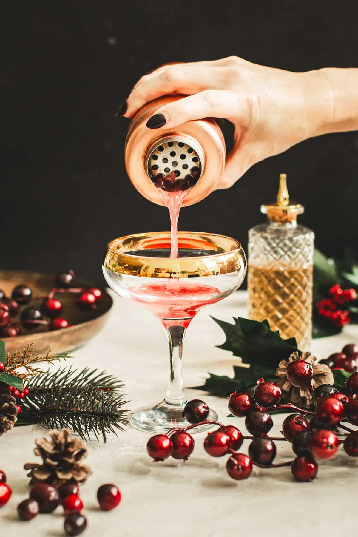 Straining a cranberry martini into a cocktail glass.