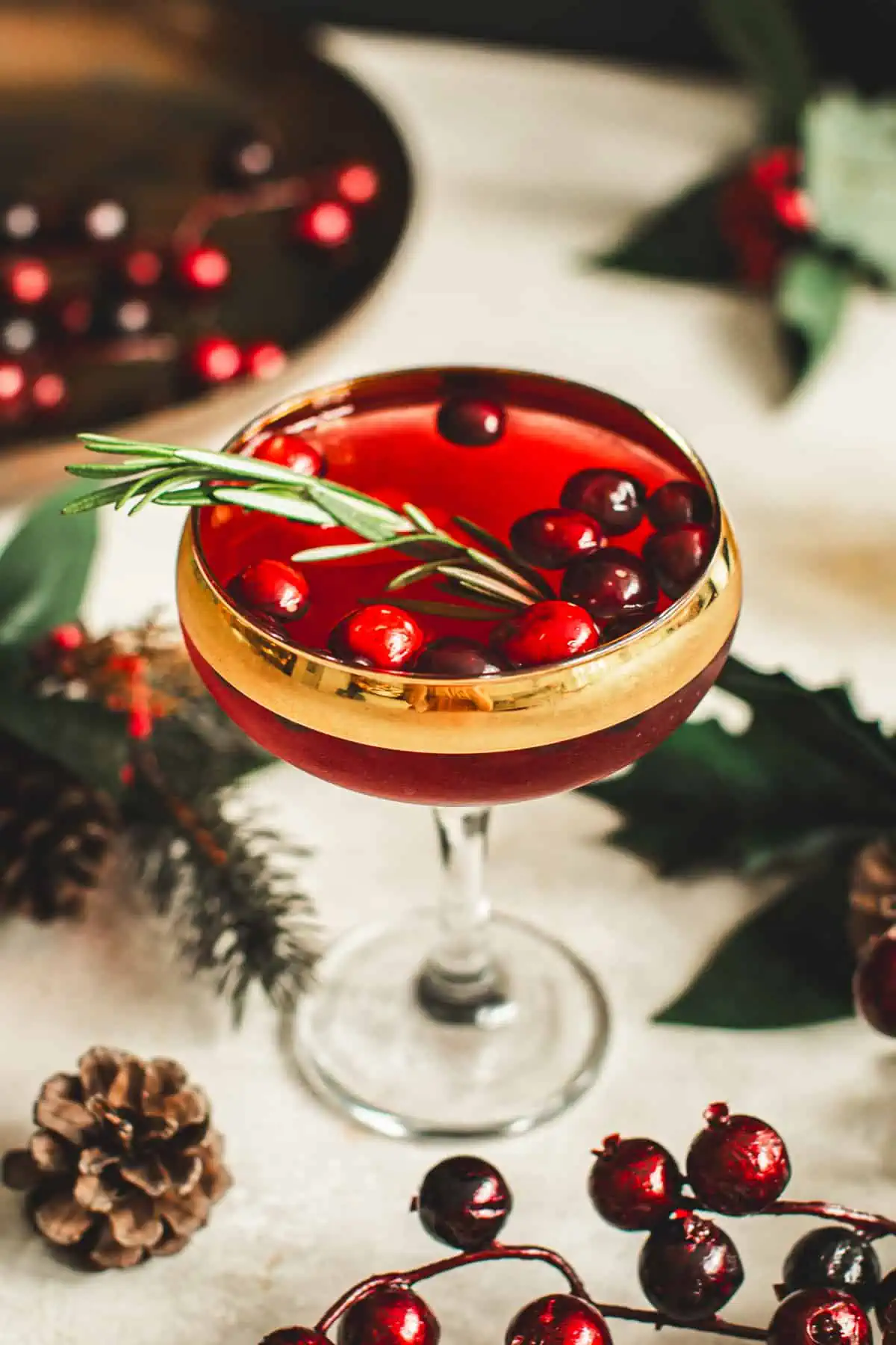 Cranberry martini with fresh cranberries and a sprig of rosemary for garnish.