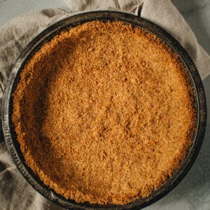 Graham cracker crust in a metal pie dish.