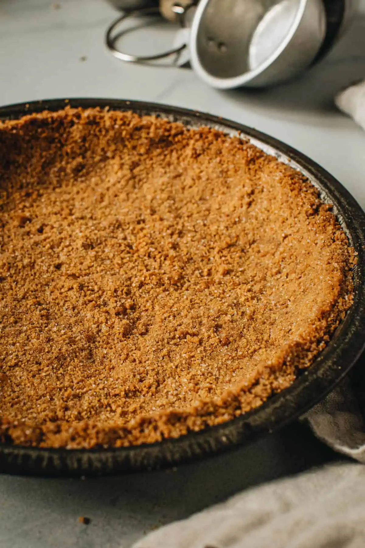 Graham cracker crust in a metal pie dish.