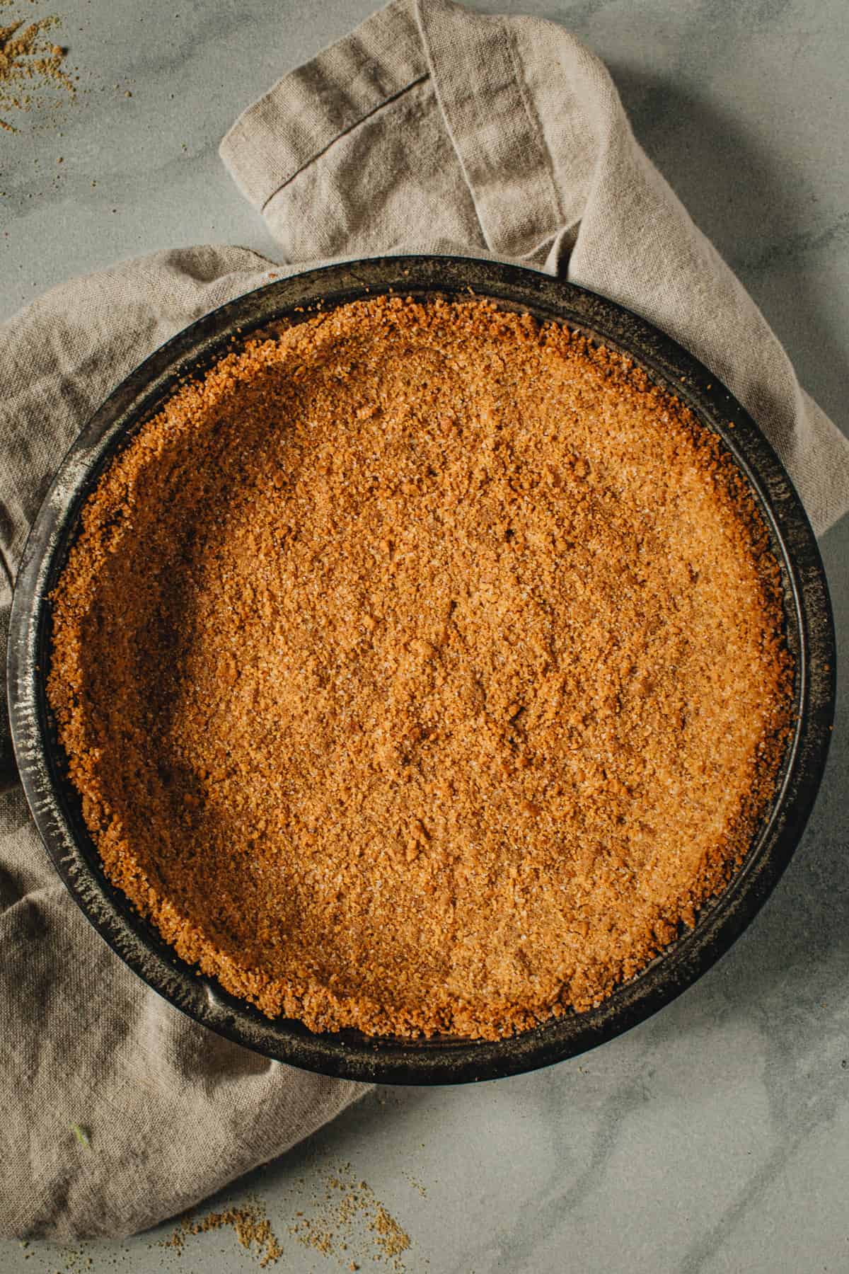 Graham cracker crust in a metal pie dish.