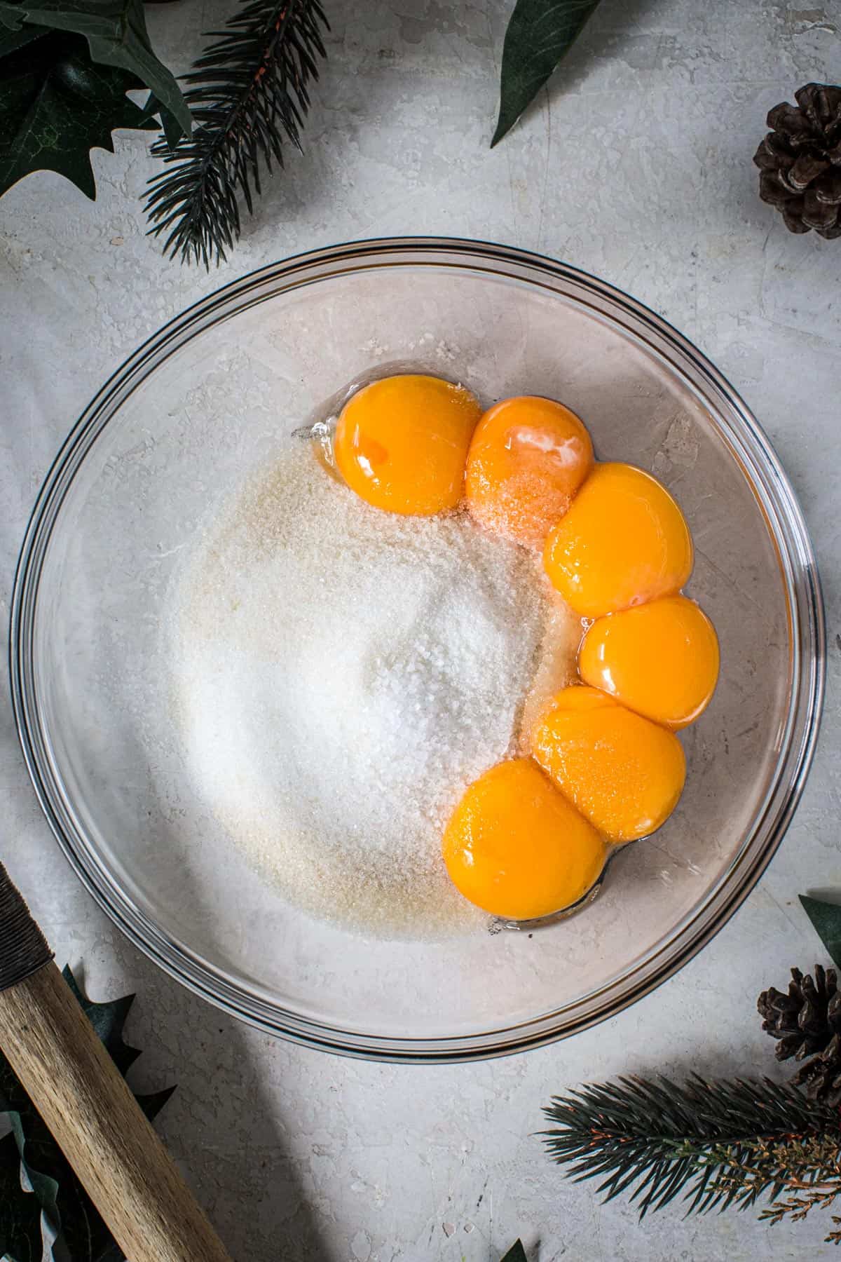 Sugar and egg yolks in a mixing bowl for making homemade eggnog.