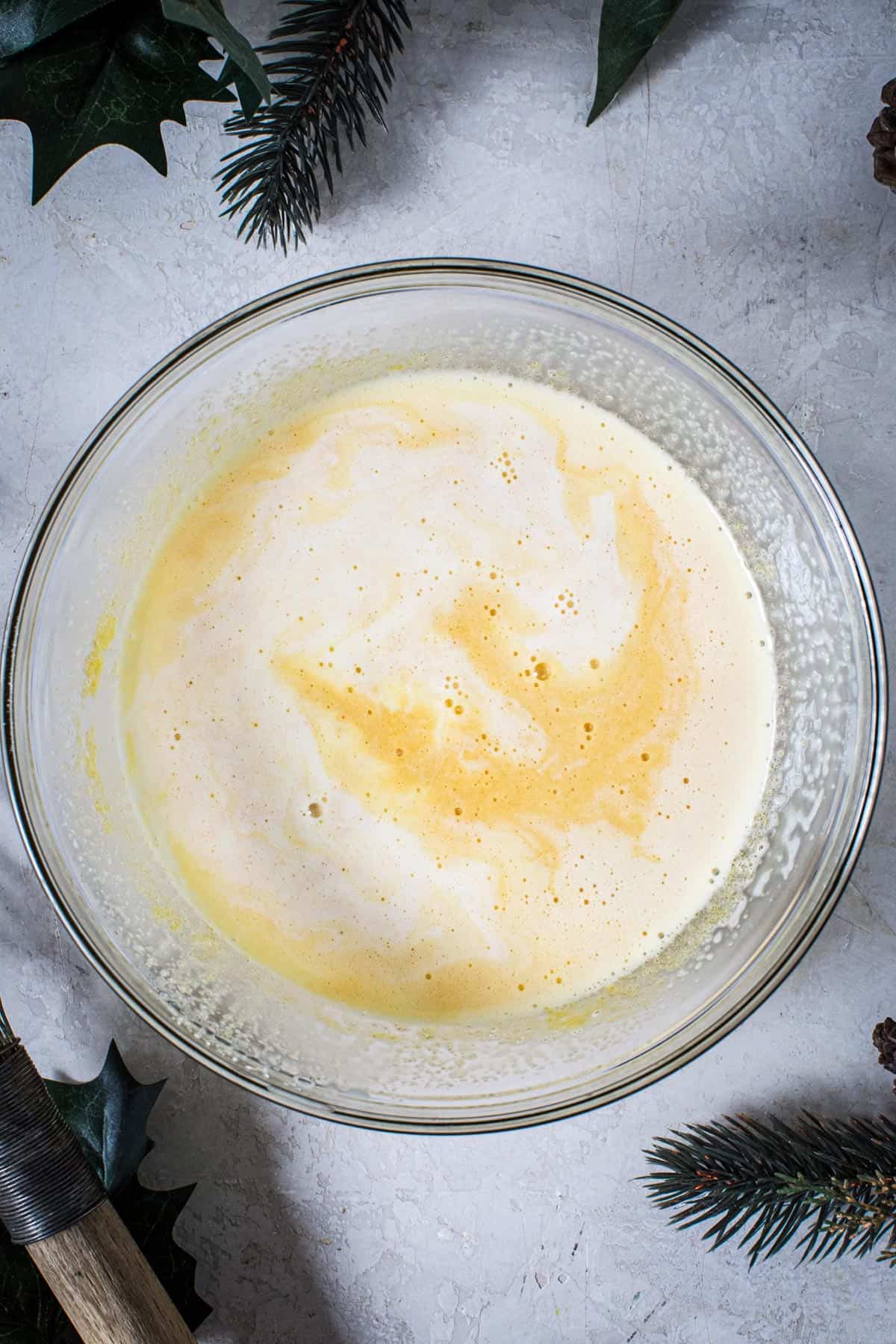 Warmed cream mixture stirred into the egg yolk mixture for making traditional eggnog.