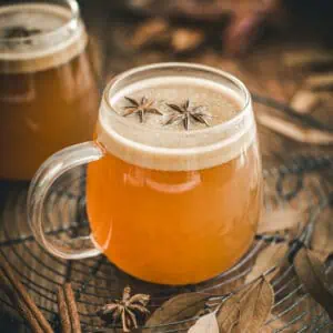 Hot buttered rum topped with star anise in a glass mug.