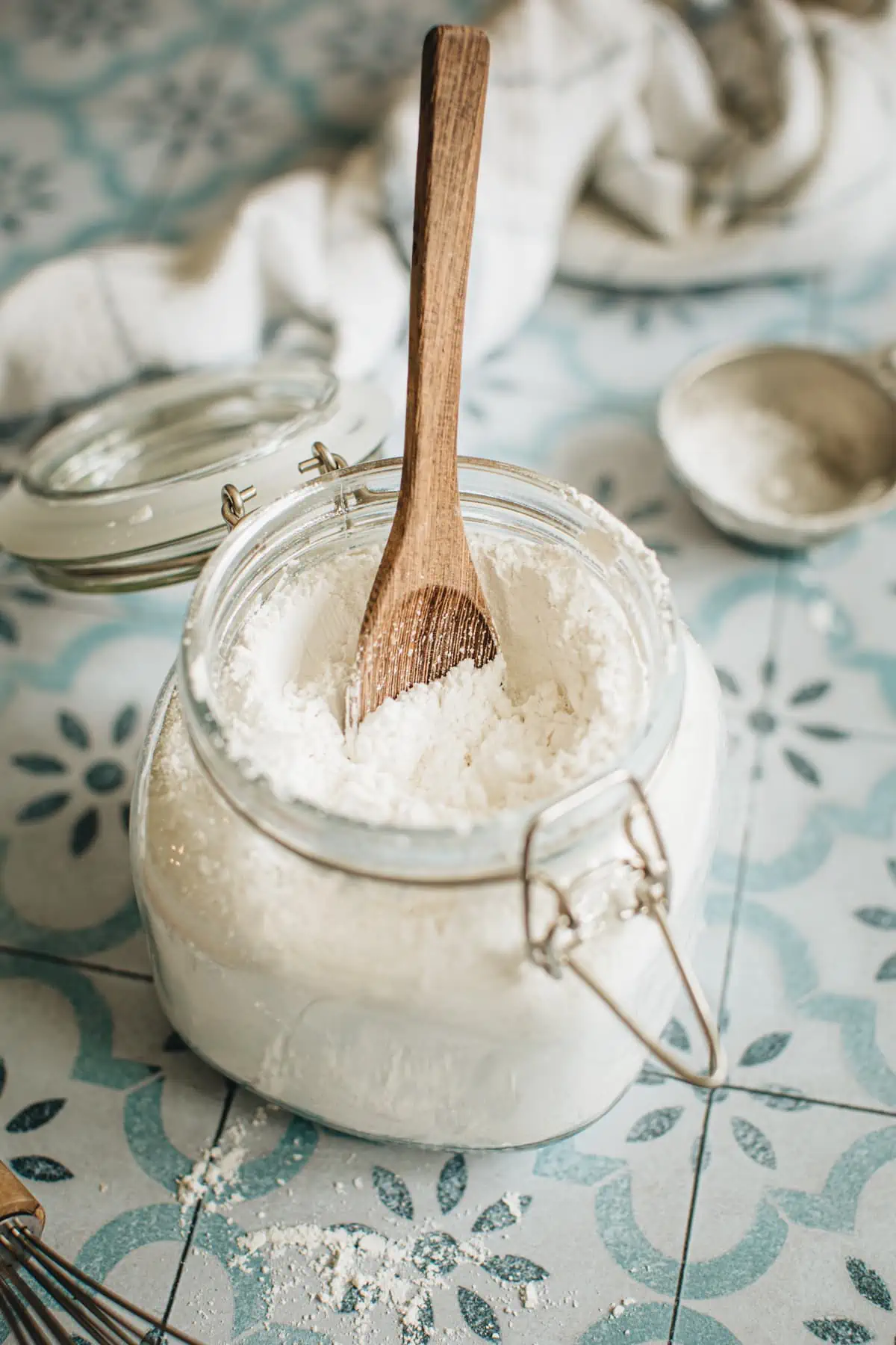 Powdered sugar in a jar with a wooden spoon in it.