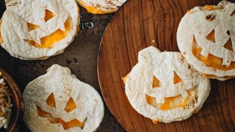 Jack-O-Lantern quesadillas on a plate and baking sheet.