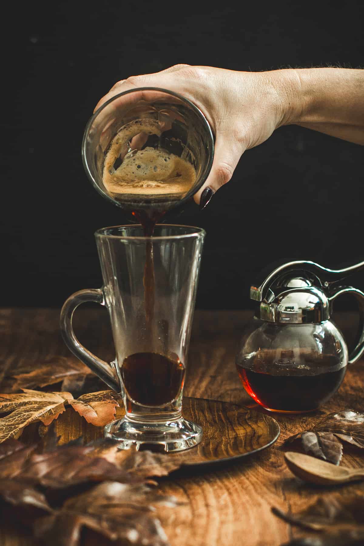 Pouring espresso into a glass mug for a maple latte.