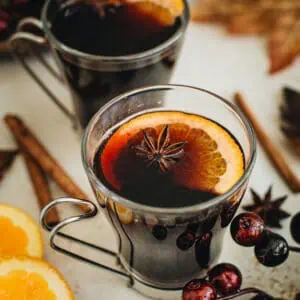 Mulled wine in a glass with an orange slice and star anise for garnish.