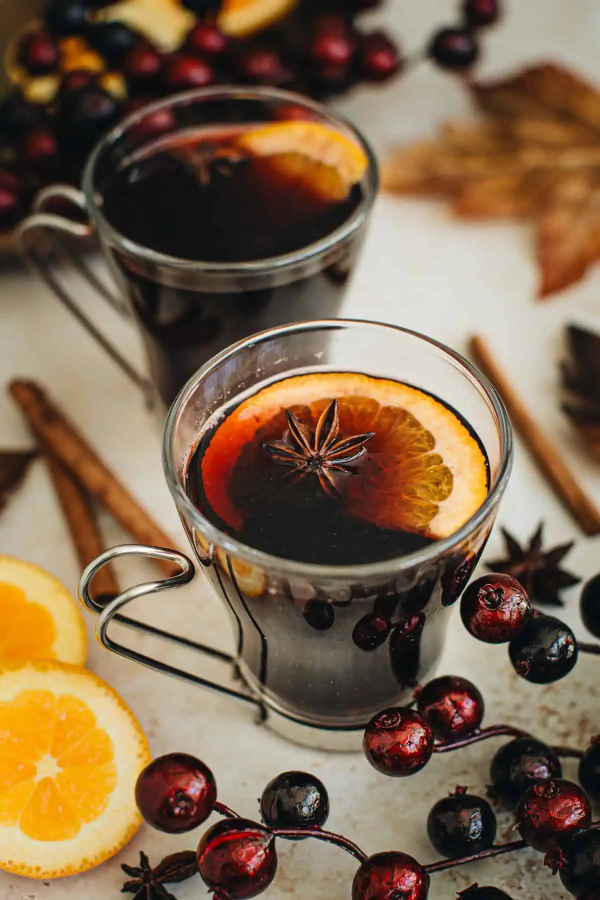 Mulled wine in a glass mug with an orange slice and star anise for garnish.