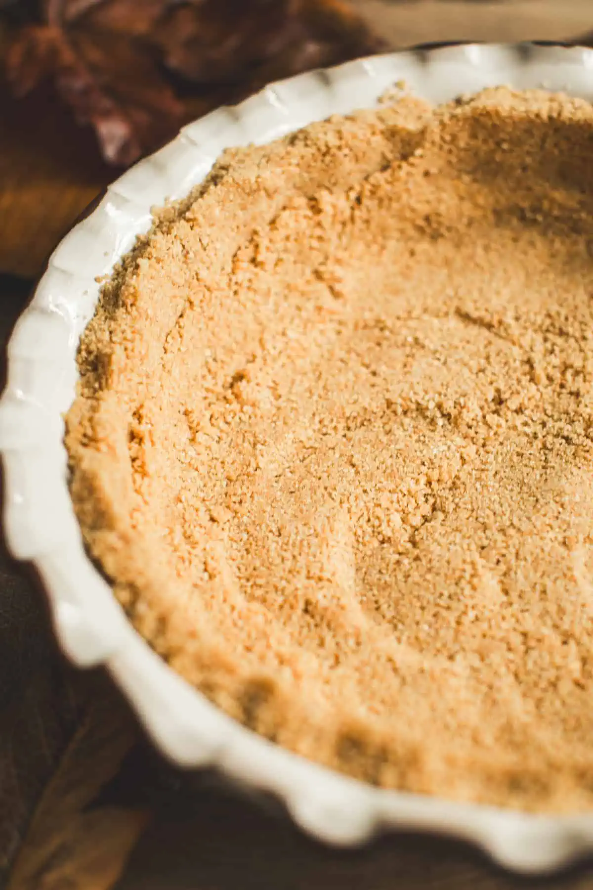 Graham cracker crust in a white pie dish for No-Bake Pumpkin Pie.