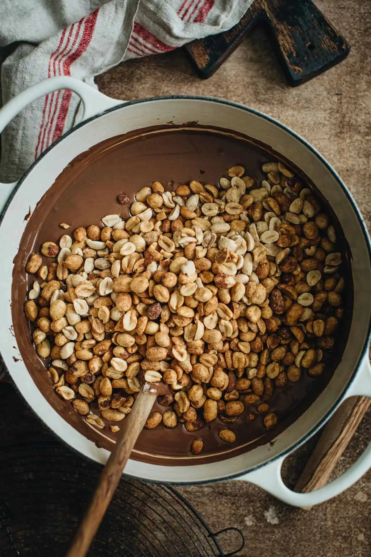 Peanuts on top of melted chocolate for making peanut clusters.