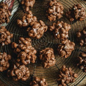Peanut clusters topped with sea salt on a round wire rack.