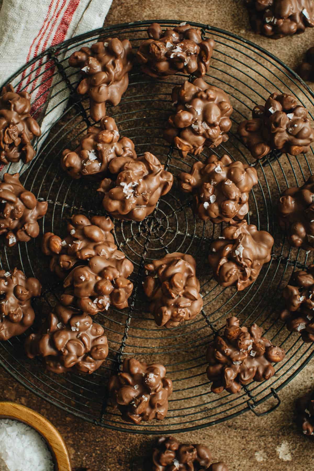 Peanut clusters topped with sea salt on a round wire rack.