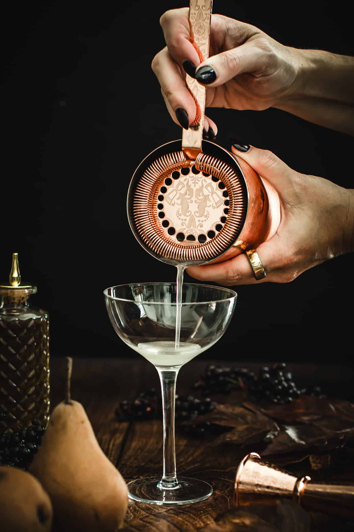 Straining a pear martini into a glass.