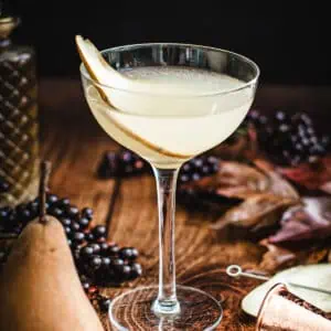 Pear martini in a glass with a fresh slice or pear for garnish.