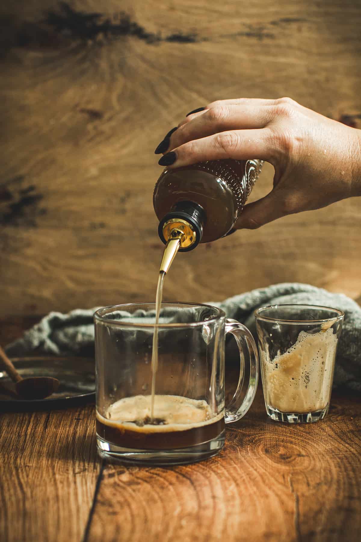 Pistachio syrup pouring over the espresso and browned butter in a coffee mug.