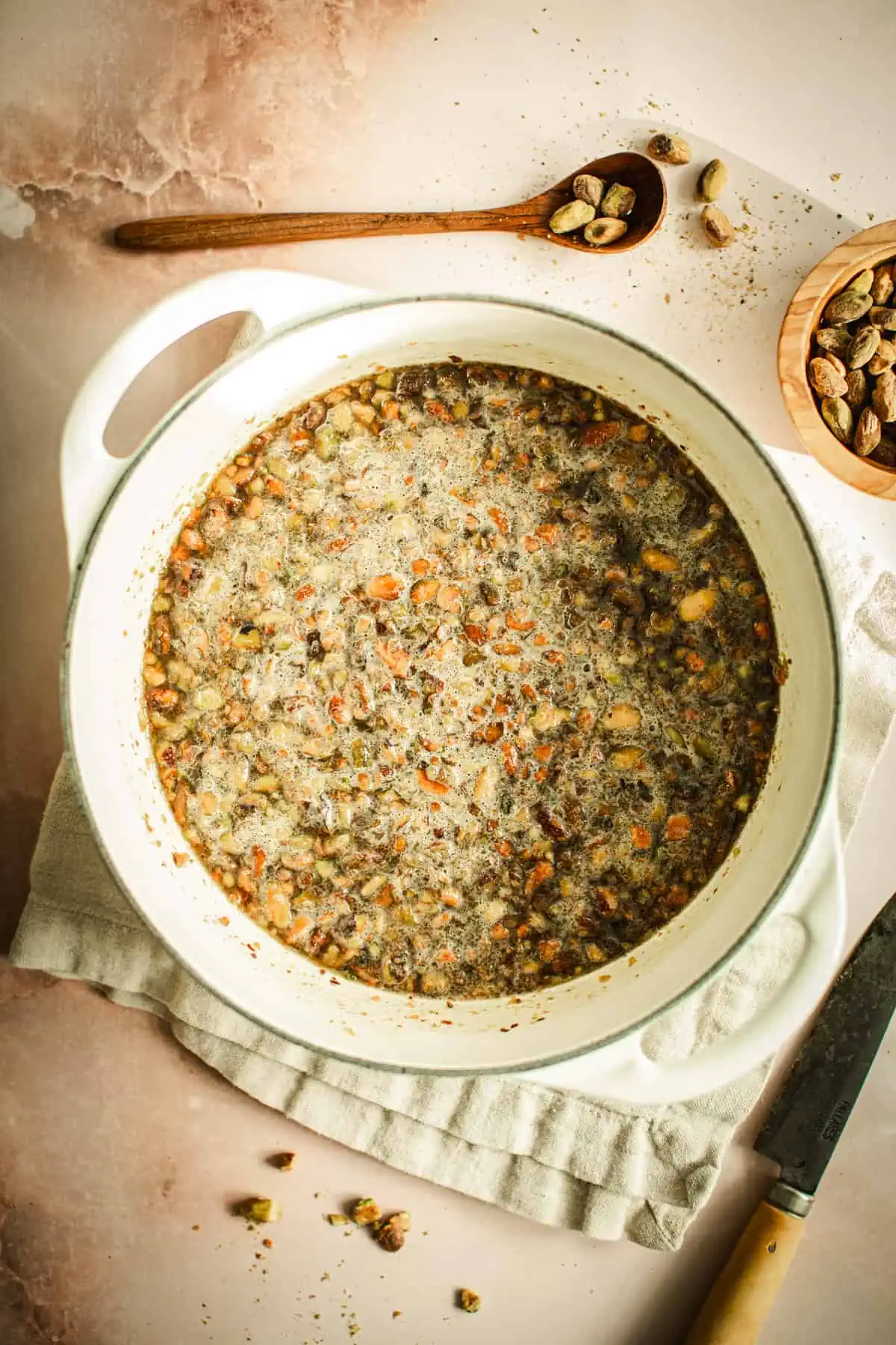 Pistachio syrup with water, sugar, and chopped pistachios cooking in a pot.