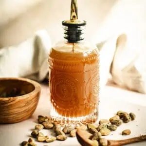 Pistachio syrup in a decorated glass bottle with a stopper spout.