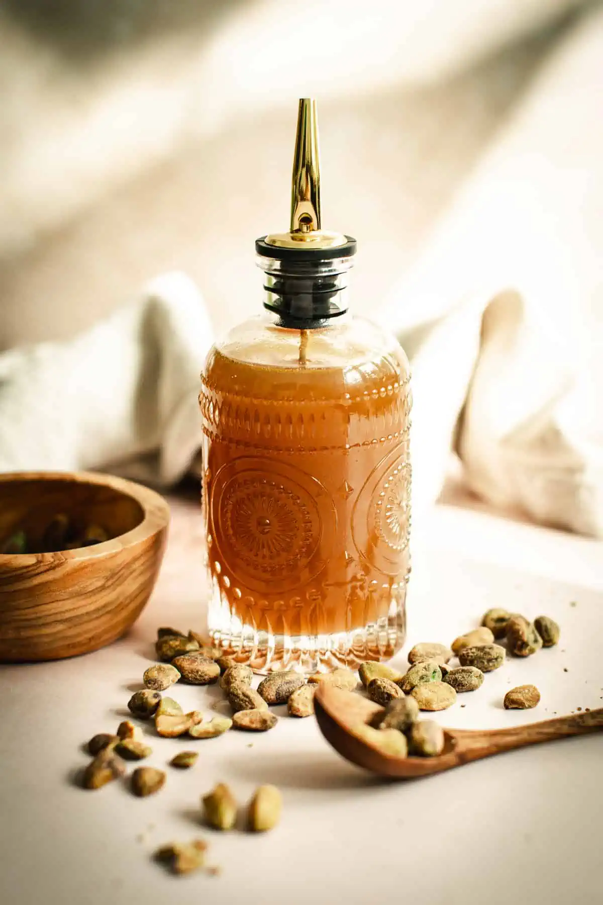 Pistachio syrup in a decorated glass bottle with a stopper spout.