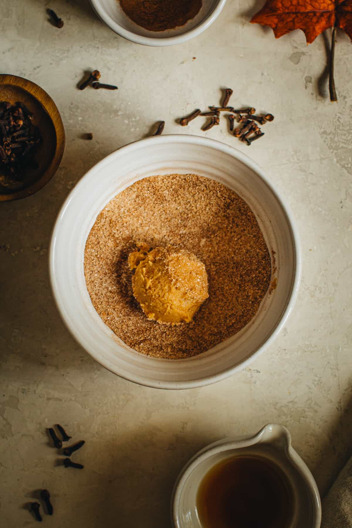 Pumpkin cookie dough ball in a cinnamon sugar mixture.
