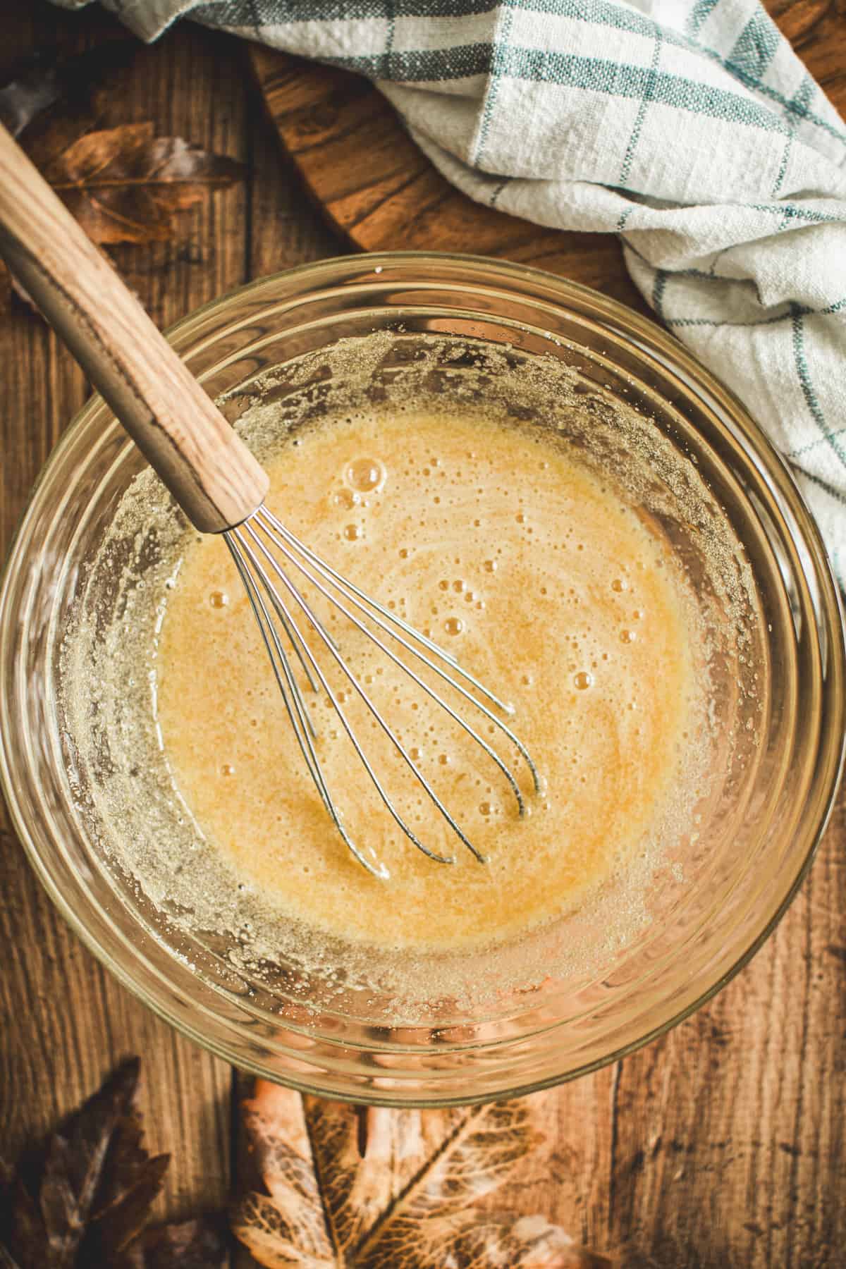 Eggs and sugar mixed in a mixing bowl with a whisk.