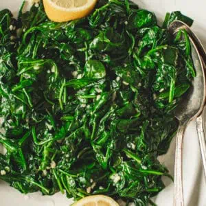 Sautéed spinach with garlic and fresh lemon on a white plate.