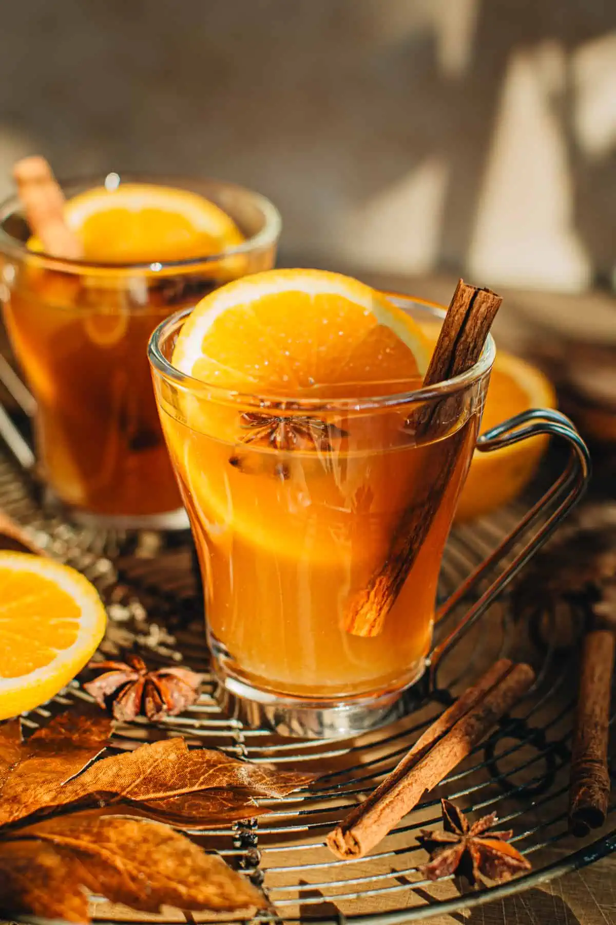 Spiked apple cider in a glass mug with a cinnamon stick, star anise, and orange slice for garnish.