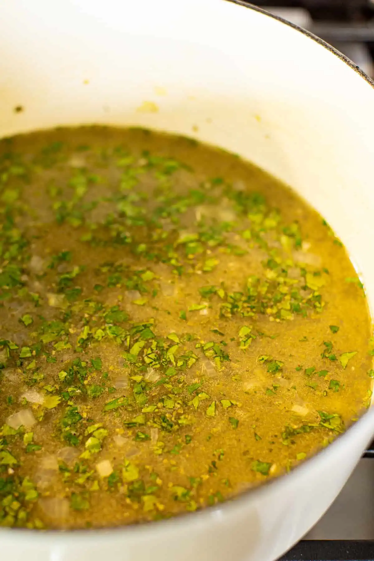 Broth for white turkey chili in a large white pot.