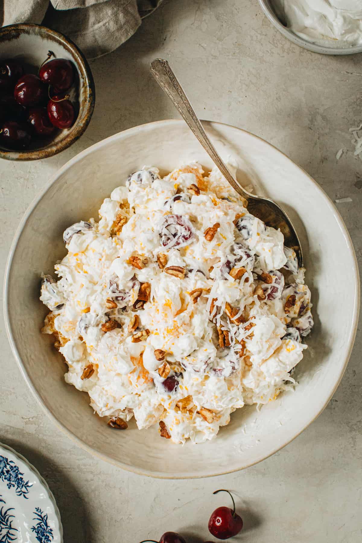 A bowl of homemade ambrosia salad ready to serve with a serving spoon.