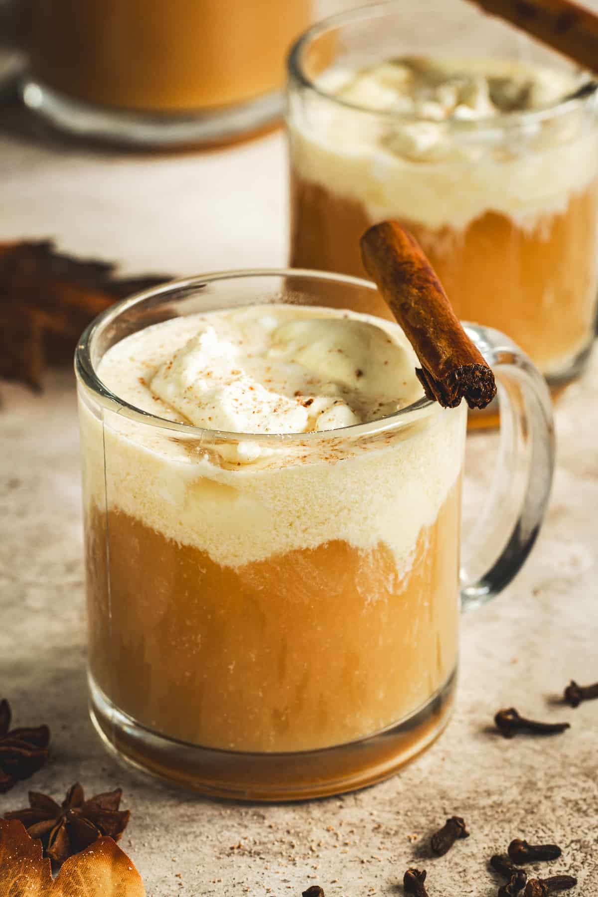 Apple Cider Bourbon Cocktail topped with whipped cream and a cinnamon stick.