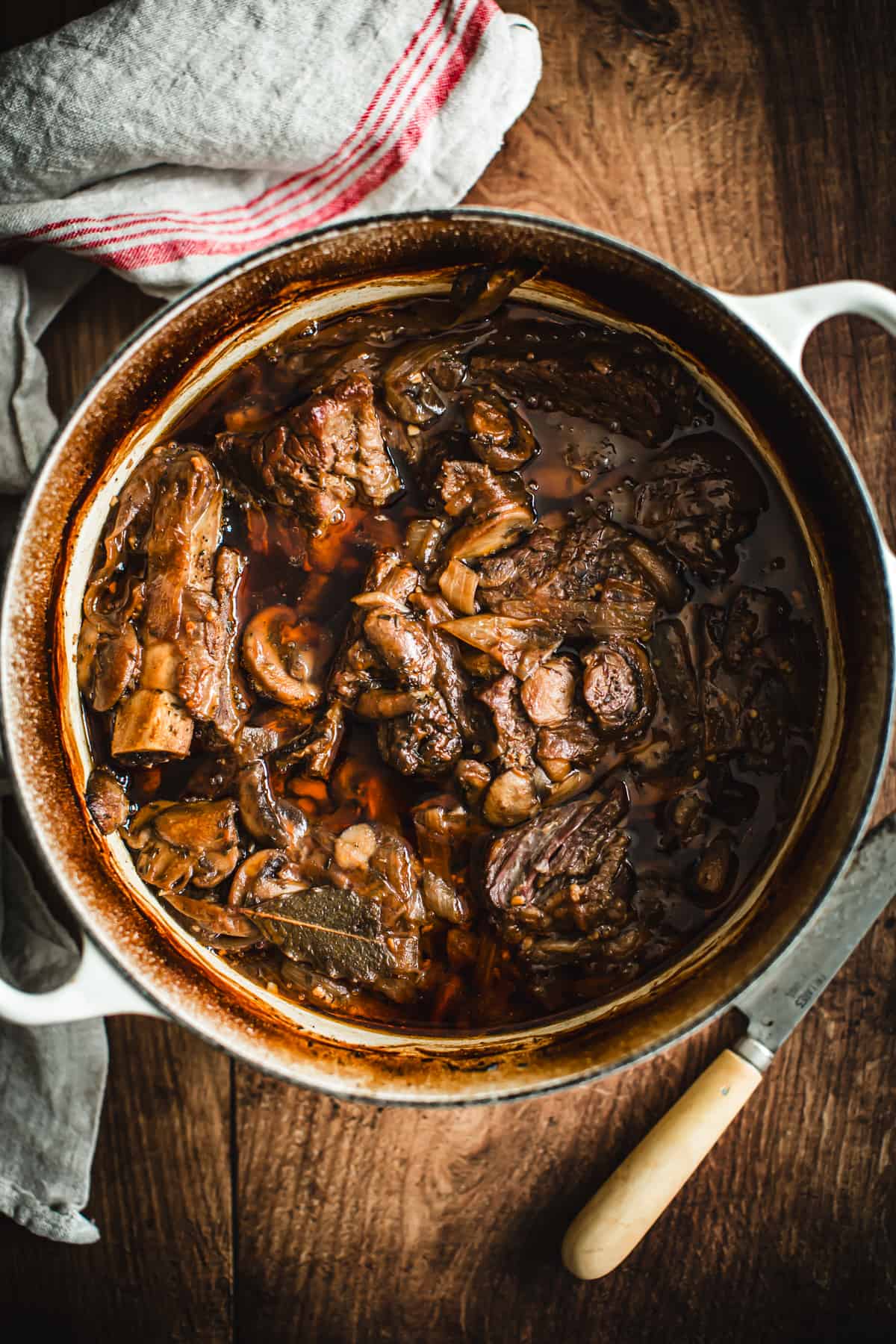 Braised short ribs in a large white pot ready to serve.